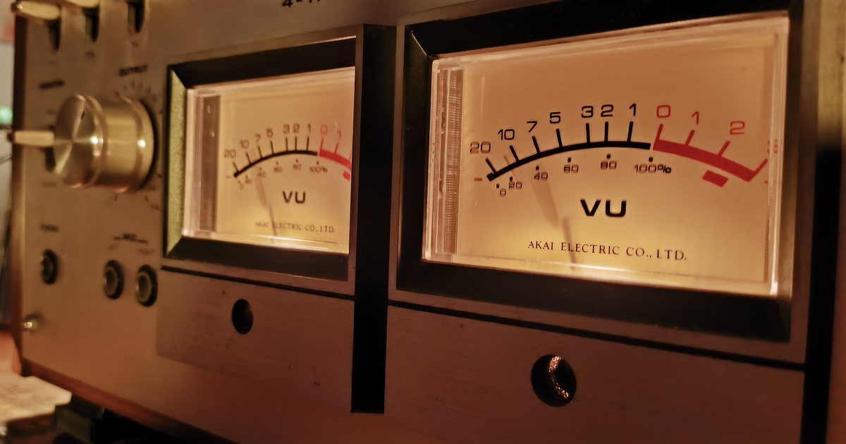 Die beiden beleuchteten VU-Meter einer AKAI-Bandmaschine im warmen Licht